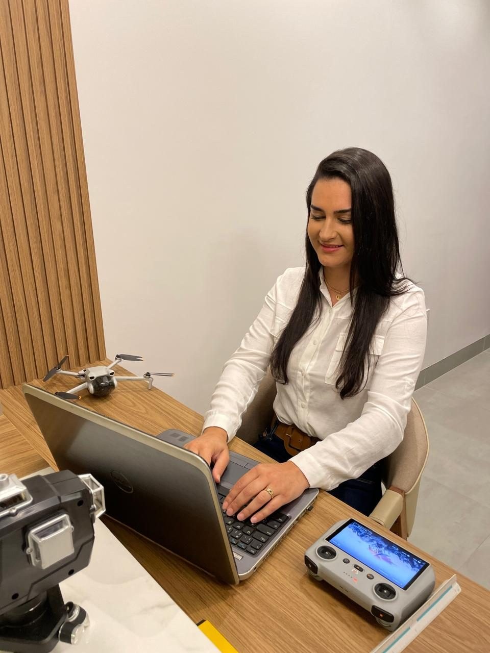 Engenheira em ambiente de escritório técnico com notebook e equipamento de vistoria